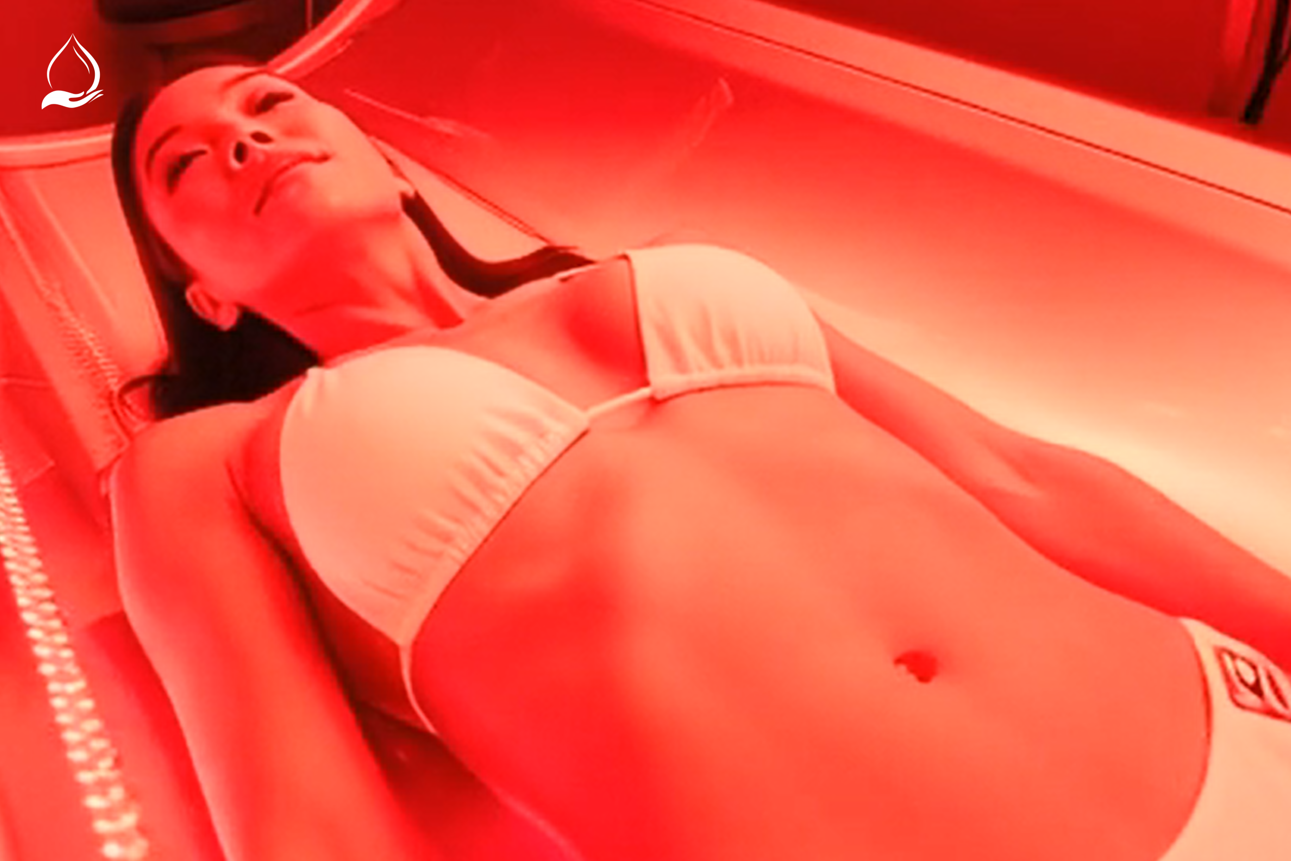 Woman relaxing in a red light therapy bed at Tinted Salt in Chandler, Arizona, receiving full-body LED treatment for skin hydration, rejuvenation, and wellness.